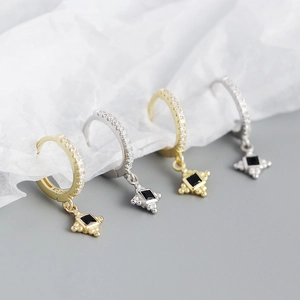 Macro detail of gold and silver S925 sterling silver star drop earrings with black stones