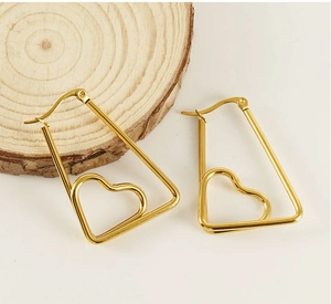 Macro shot of gold heart-shaped earrings with a hollow geometric trapezoid frame