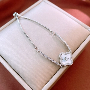 Macro shot of silver four-leaf clover bracelet with white shell inlay and adjustable chain