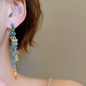 Close-up of dangling earrings featuring colorful teardrop crystals on female model