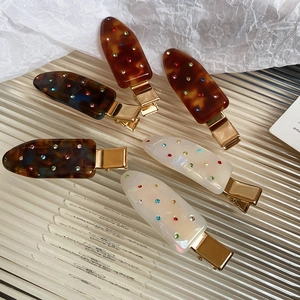 Detail of acrylic rhinestone hair clips in tortoise shell and pearl white finish