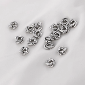 Primer plano de cuentas de metal plateado en forma de nudo para joyería artesanal