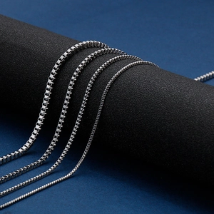 Detail of silver stainless steel box chains draped over a black cylindrical display