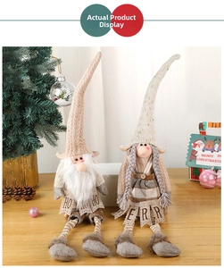 Close-up of two Christmas gnomes with knitted hats holding HO HO HO and MERRY flags
