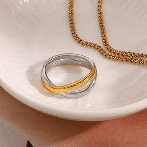Minimalist bicolor stainless steel intertwined ring on elegant white ceramic dish
