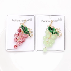 Détail de broches de raisin avec feuilles émaillées et cristaux sur carte de support