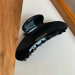 Close-up of a large black curved hair claw clip with golden France Handmade lettering