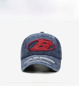 Detail of red embroidered B logo and white text on navy washed denim baseball cap
