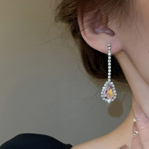 Close-up of pink pear-cut drop earrings with silver diamond pavé setting on model