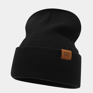Close-up of black knit beanie featuring a brown leather patch with DAD lettering