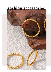 Macro shot of gold-plated beaded rings on dark wood and white textured background