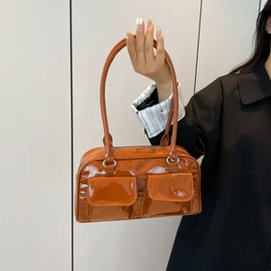 Detail view of glossy caramel patent leather tote bag with two front flap pockets
