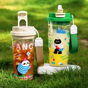 Outdoor shot of portable panda and black cat coffee tumblers on grass with lanyards