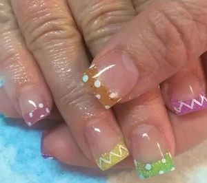 Gros plan d'ongles French colorés avec des pois blancs et des motifs en zigzag au bout