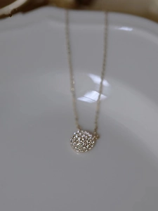 Macro view of gold S925 sterling silver necklace with sparkling pave round pendant