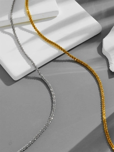 Close-up of gold and silver sparkling star link chain necklaces on a modern stone base