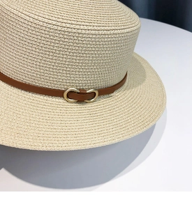 Close-up of beige straw boater hat with brown leather band and gold metal buckle