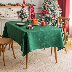 Dark green rectangular Christmas tablecloth with snowflake pattern on a wooden table