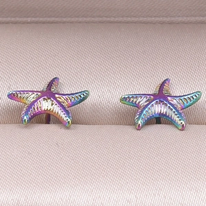 Macro detail of iridescent starfish earrings on champagne silk jewelry lining