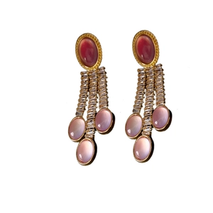 Orecchini vintage dorati con pietre ovali rosa e nappe di zirconi su sfondo bianco