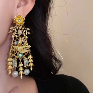 Close-up of vintage flower and bird earrings with faux pearls and crystals on a model