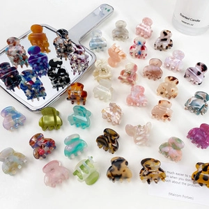 Flat lay of mini acetate claw clips in marble and tortoiseshell patterns on a white table