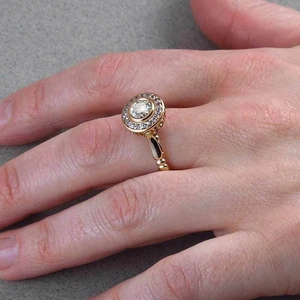 Detail of a gold-plated engagement ring with a round center diamond on a hand