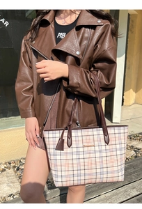 Close-up of classic checkered print tote bag with brown leather straps and metal logo