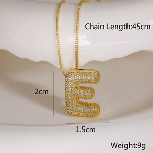 Close-up of gold letter E necklace pendant with cubic zirconia on a box chain