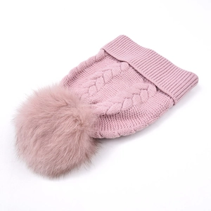 Bonnet en maille rose pour femme avec un grand pompon en fausse fourrure sur fond blanc