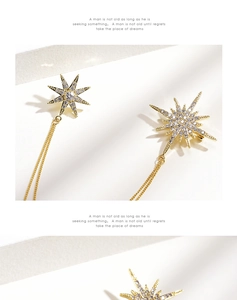 Close-up of golden starburst earrings with sparkling crystals and long chain tassels