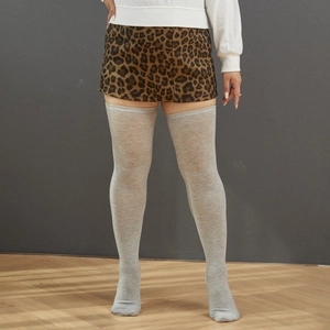 Close-up of light grey knit over-the-knee socks paired with a leopard print mini skirt