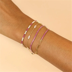 Set aus stapelbaren Gold-Tennisarmbändern mit rosa und weißen Steinen am Handgelenk