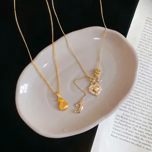 Zircon lucky bag and heart necklace set in gold finish on white ceramic display plate