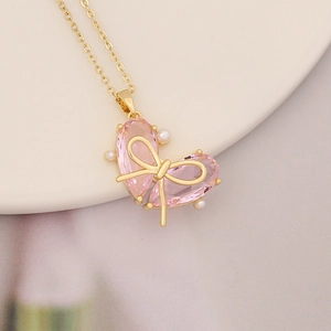 Macro shot of pink heart crystal pendant with gold butterfly bow and small pearls