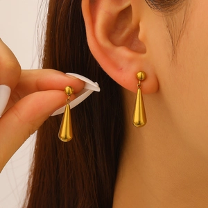 Nahaufnahme eleganter goldener Wassertropfen-Ohrringe am Modell mit polierter Metalltextur
