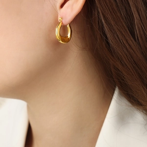 Elegant gold U-shaped geometric earrings in polished titanium steel worn by a model