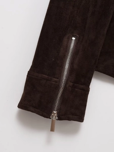 Detailed close-up of dark brown suede cuff with polished silver metal zipper closure