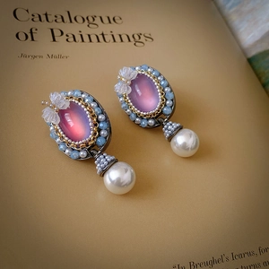 Detail of pink crystal and pearl earrings with blue beads on a vintage book page
