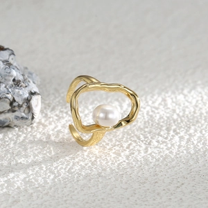 Adjustable gold shell pearl ring in minimalist open design on textured background