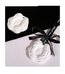 Macro detail of white camellia plaster diffuser with elegant black satin ribbon