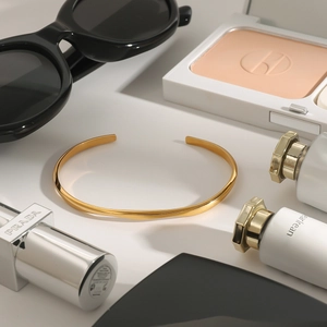Close-up of a minimalist gold C-shaped stainless steel cuff bracelet with a polished finish