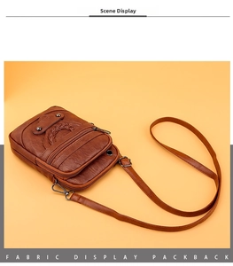 Detail of a brown leather crossbody phone bag with woven pattern and zipper pockets