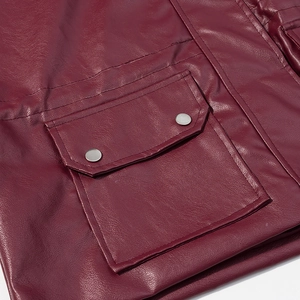 Detailed close-up of burgundy leather jacket pocket with metallic snap buttons