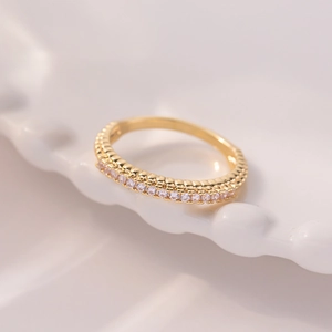 Detail of minimalist gold eternity ring with single row micro-pave cubic zirconia crystals
