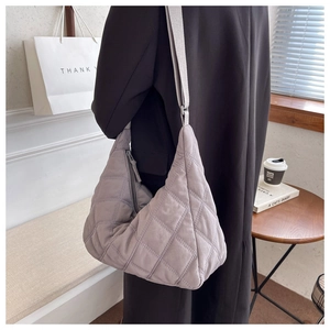 Detailed view of light gray quilted nylon crossbody bag with adjustable strap on model