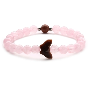 Pink quartz beaded bracelet with brown goldstone and butterfly charm on white background
