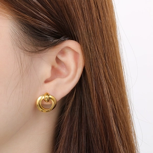Close-up of model wearing gold interlocking double hoop earrings in polished finish