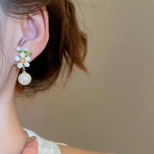 Detail von 18k vergoldeten Blumenohrringen mit Perle und Zirkonstein am weiblichen Model