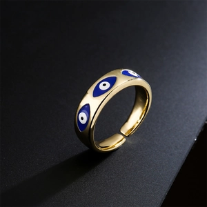 Golden evil eye open ring with blue and white enamel inlay on a dark surface